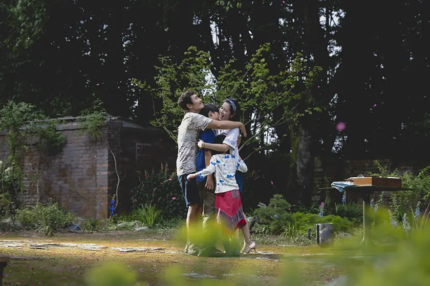 Man-su (Lee Byung-hun) and Miri (Son Yejin) hug their children in No Other Choice (어쩔수가없다)