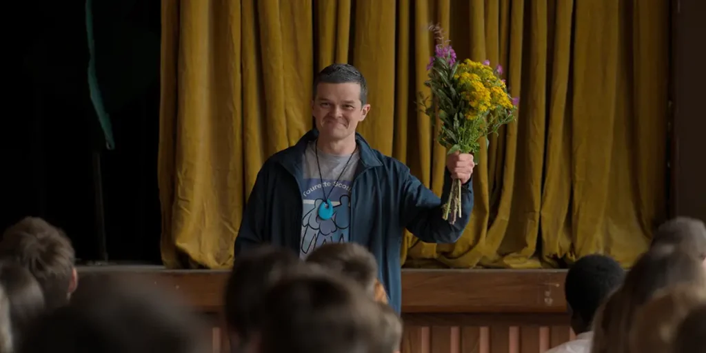 Robert Aramayo holds flowers in a still from the movie I Swear
