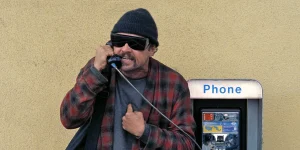 Leonardo Di Caprio is on the phone wearing sunglasses in One Battle After Another