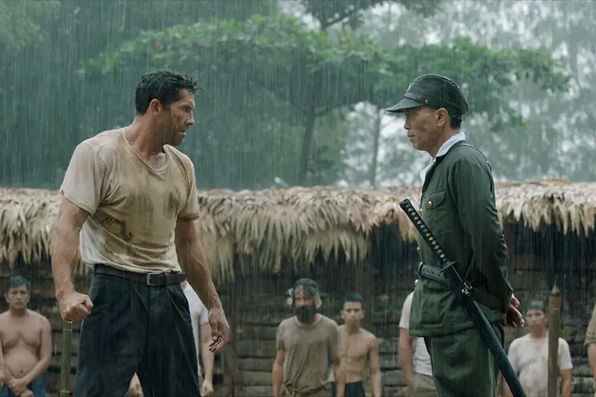 Two men face under the rain in a still from Prisoner of War