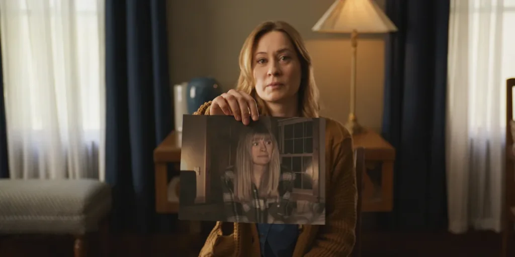 A woman holds up a picture of a younger woman in a still from the movie Shelby Oaks