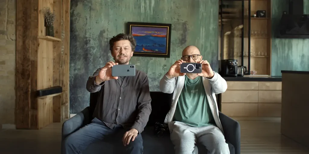 Two men take photos with their phones in a still from To The Victory!