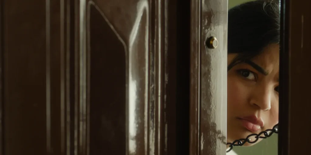 Mila Alzahrani looks out from behind a door in a still from the film Unidentified