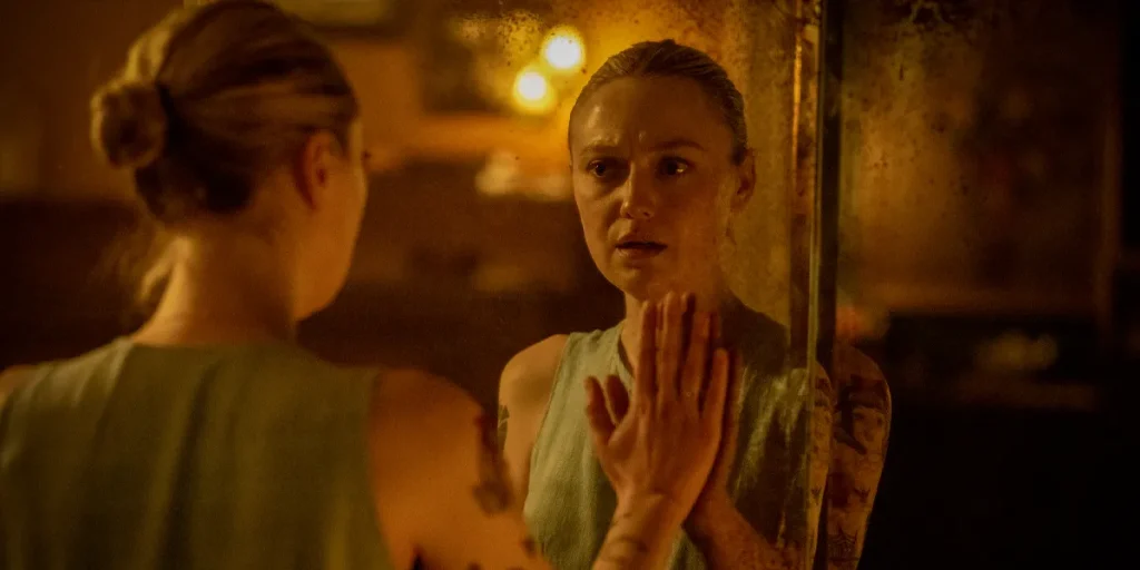 Dakota Fanning places a hand on a mirror and looks at her reflection in the 2025 movie "VICIOUS."