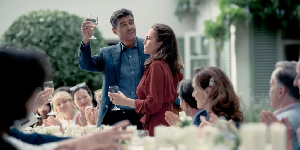 Two people make a toast at a table in the 2025 movie "Anniversary"