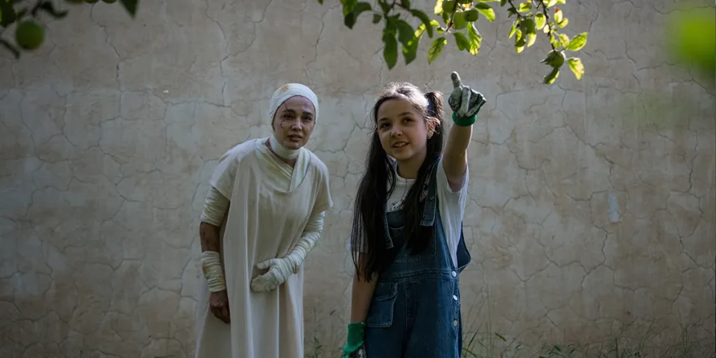 Two women stand, one of them pointing at a tree, in a still from the film Black Rabbit, White Rabbit