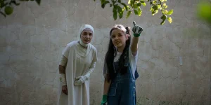 Two women stand, one of them pointing at a tree, in a still from the film Black Rabbit, White Rabbit
