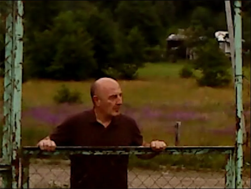 A man looks from across a barricade in a still from the film Dry Leaf