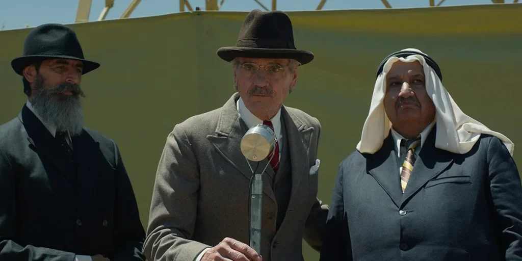 Jeremy Irons speaks with two men at his sides in Palestine 36