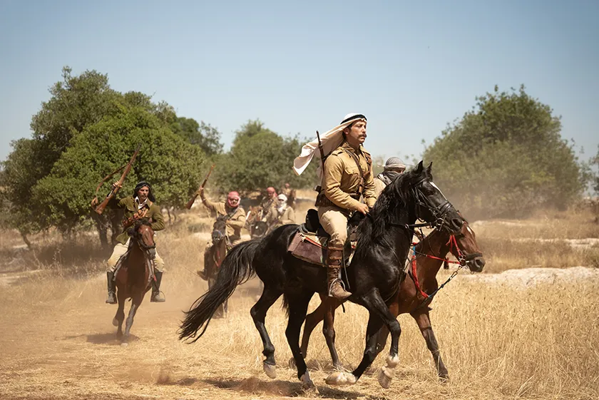 A man is on a galloping horse with other men behind him in Palestine 36