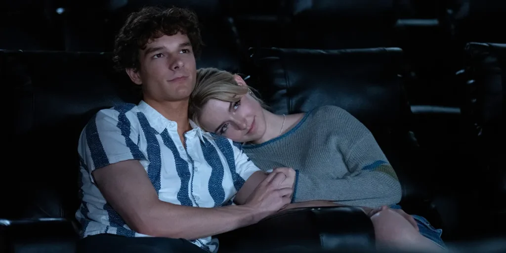 A boy and a girl lean close to each other at the cinema in a still from Regretting You