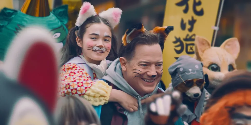 Brendan Fraser and Mia Kawasaki wear animal ears and face paint in a still from the film Rental Family
