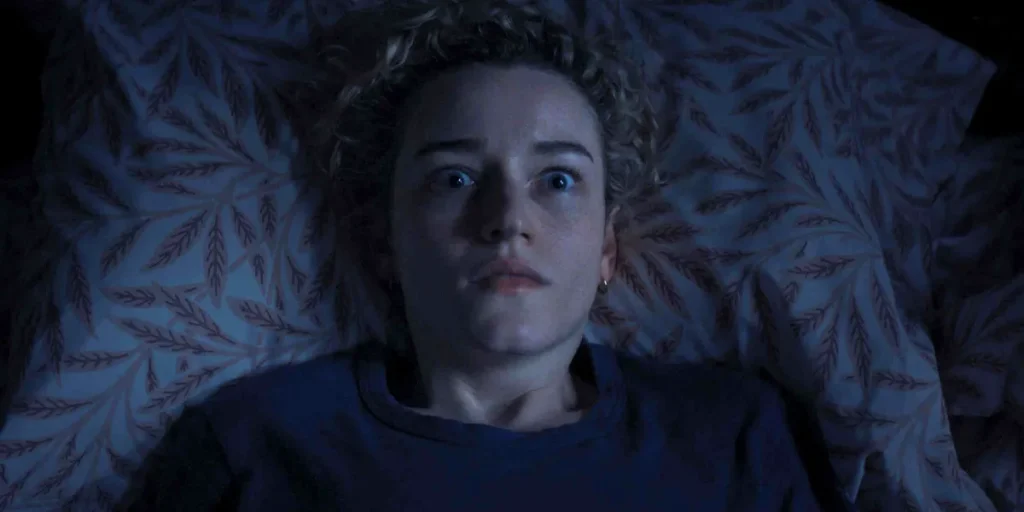 Julia Garner lies in bed wide-eyed in a still from the movie Weapons