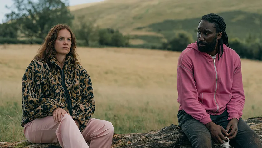 Ruth Wilson and Nathan Stewart-Jarrett sit on a wooden bench in "Down Cemetery Road"