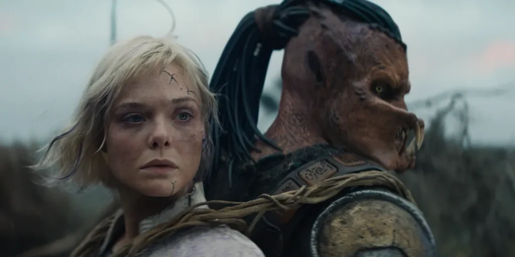 Thia (Elle Fanning) and Dek (Dimitrius Schuster-Koloamatangi) stand back to back in a still from the movie Predator: Badlands