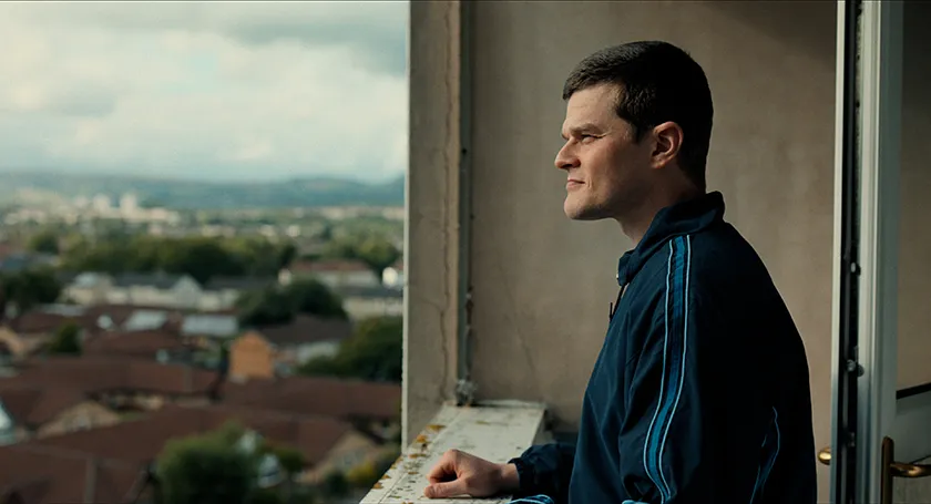 Robert Aramayo, whom we interview alongside Kirk Jones, looks out of a window in a still from I Swear