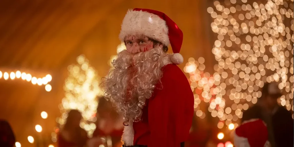 A young man in a Santa suit has blood on his face in a still from the 2025 slasher horror movie "Silent Night, Deadly Night"