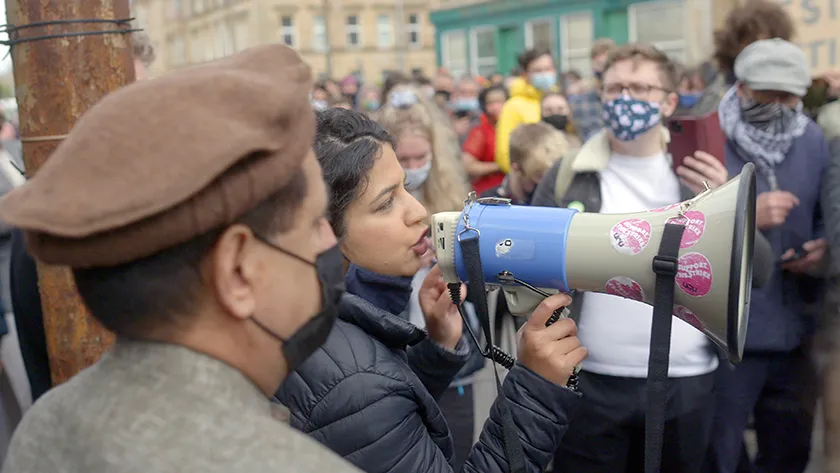 A woman shouts into a megaphone in a still from Everybody To Kenmure Street by Felipe Bustos Sierra, an official selection of the 2026 Sundance Film Festival