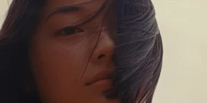 Michelle Mao looks into the camera with a desaturated yellow background behind her in Kogonada's film Zi (2026)