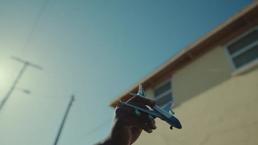 A hand holds a toy plane in a still from If I Go Will They Miss Me
