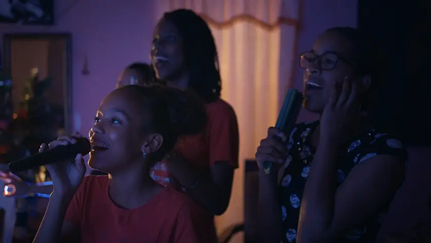 Girls sing in a house, smiling, in a still from the 2026 movie Agridulce (Bittersweet)