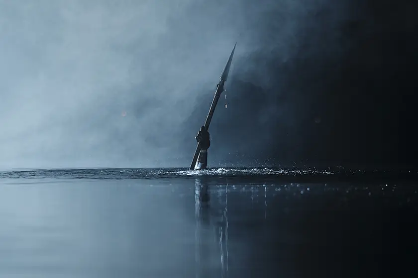 A hand holds a spear in the water in a still from the 2026 movie Teenage Sex and Death at Camp Miasma