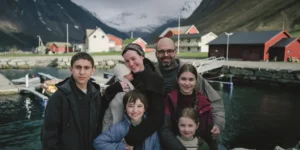 A still from the movie Fjord portraying a happy family smiling and posing for a picture in front of the Alps