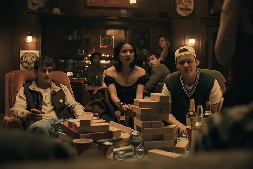 Michael Johnston as Bear, Megan Lawless as Sarah and Cooper Tomlinson as Ian play games in a still from the 2026 movie Obsession