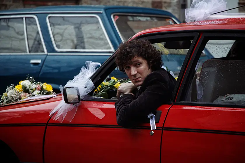 Vincent Lacoste, whom we interview with Christophe Honoré, Adèle Exarchopoulos, is in a red car in a still from their movie Orange-Flavoured Wedding (Mariage au Goût d'Orange)