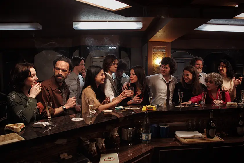 Adèle Exarchopoulos and Vincent Lacoste, whom we interview with director Christophe Honoré, are at a pub with a lot of other people in a still from the movie Orange-Flavoured Wedding (Mariage au Goût d'Orange)
