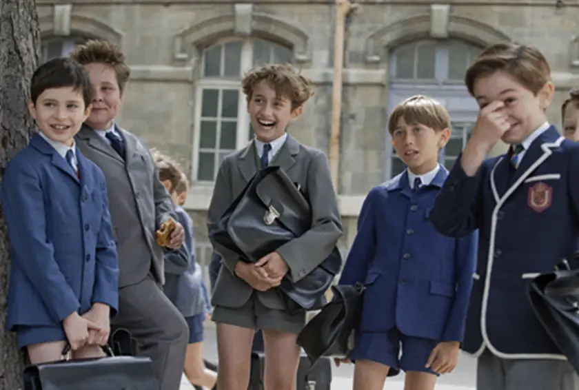 Nicolas smiles mischeviously surrounded by his classmates in a still from Le Petit Nicolas (2009)