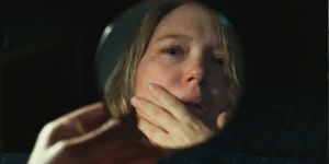 Lea Seydoux looks at her own face in a round handheld mirror in a still from The Unknown (L'Inconnue)