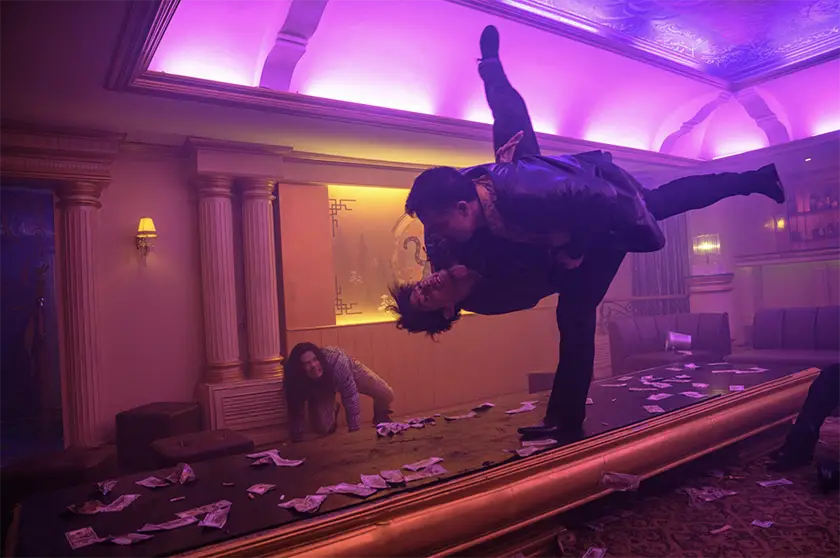 Two men fight on a table mid-air in a still from the movie The Furious