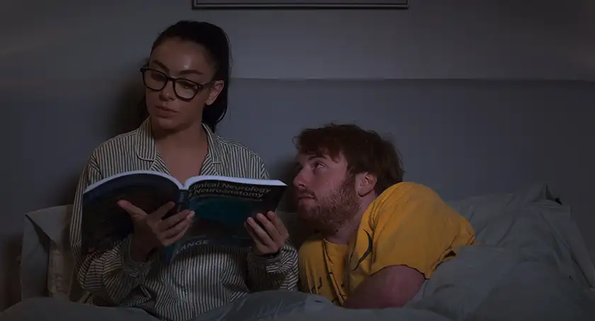 Charli XCX is reading a book in bed and Cooper Hoffman is looking at her with desire in the 2026 movie I Want Your Sex