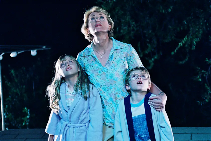 A woman and her two children look up standing outdoors at nighttime in a still from the film Mysterious Skin