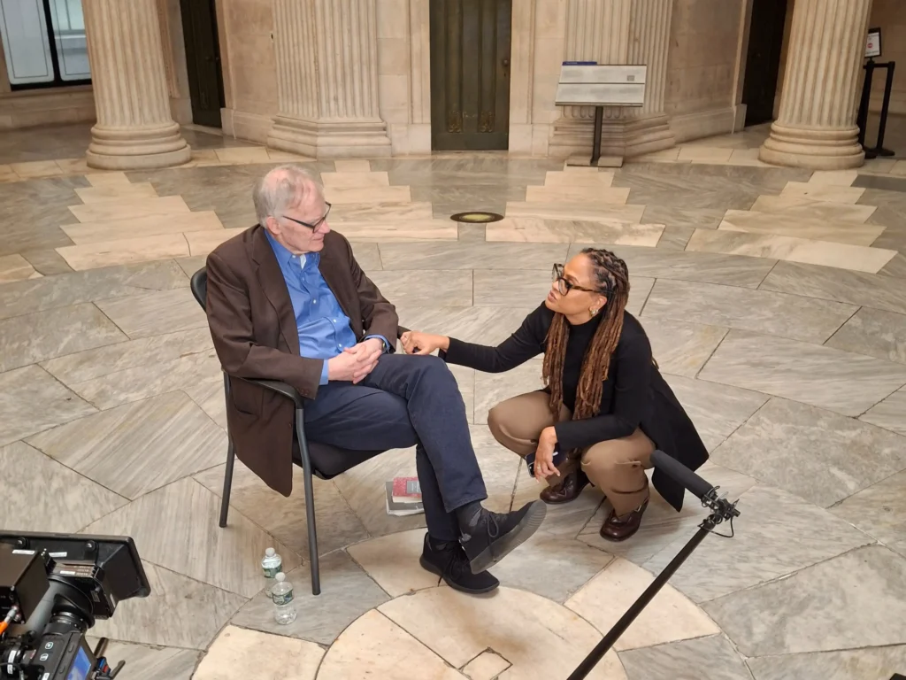 Ava DuVernay shakes someone's hand while filming the movie 14th